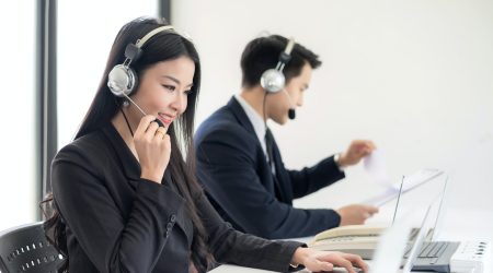 Operator in headphones with microphone consulting client on laptop in customer support service.